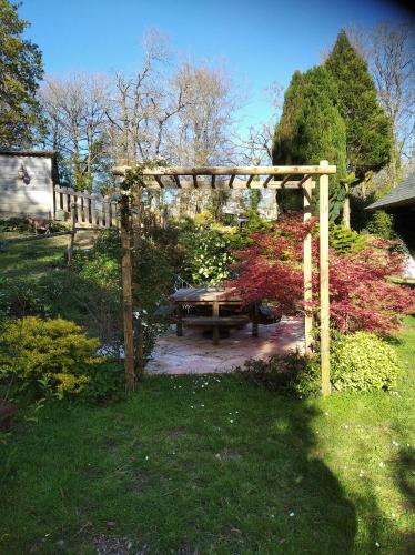 a wooden pergola and a picnic table in a garden at Maison dans un environnement boisé très calme in Morlaix