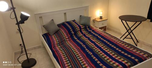 - une chambre avec un lit et une couverture colorée dans l'établissement Appartement près de la mer, à Sète