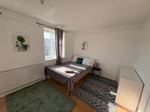 a small bedroom with a bed and a window at Essex Apartment in Loughton