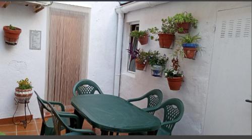 a green table and chairs on a patio with potted plants at El Almazán in Buñol