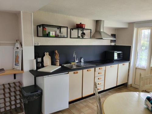 une cuisine avec des armoires blanches et un évier dans l'établissement saint lunaire, à Saint-Lunaire