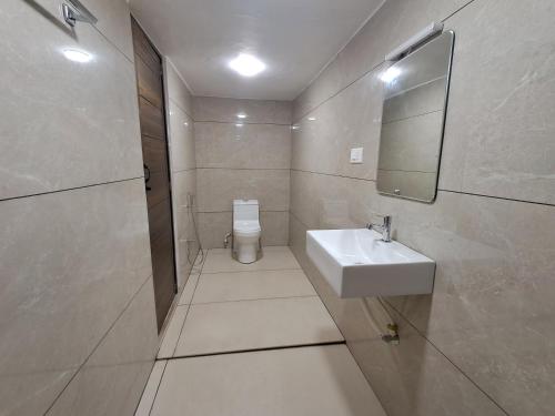 a bathroom with a sink and a mirror and a toilet at Raj Villa in Trivandrum