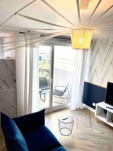 un salon avec un canapé bleu et une grande fenêtre dans l'établissement Flanelles - beautiful apartment Lyon 8, à Vénissieux