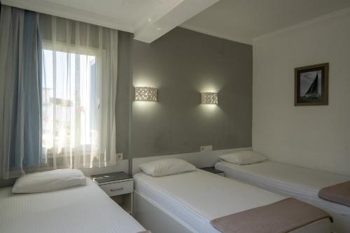 two beds in a room with a window at Artunc Hotel Bodrum in Bodrum City