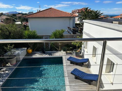 d'un balcon avec une piscine et deux chaises bleues. dans l'établissement Belle Villa, piscine chauffée à 250m des plages, à Biarritz