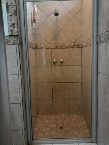 una ducha con puerta de cristal en un baño en TANS Guest suite, en Centurion
