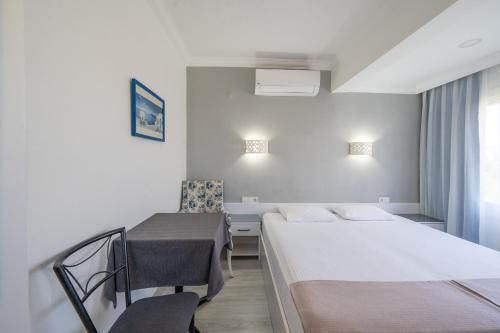 a hotel room with two beds and a chair at Artunc Hotel Bodrum in Bodrum City