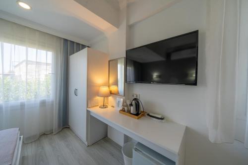 a white room with a table with a television on a wall at Artunc Hotel Bodrum in Bodrum City