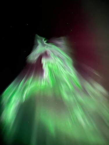 a person standing on top of a mountain with green lights at Haven Islands Treehouse on a private island in Torrflonäs