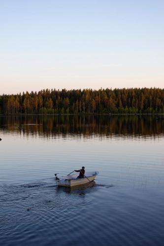 a man is rowing a boat on a lake at Haven Islands Treehouse on a private island in Torrflonäs