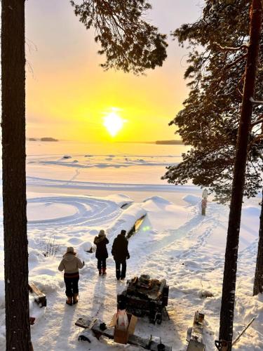 three people walking in the snow at sunset at Haven Islands Treehouse on a private island in Torrflonäs