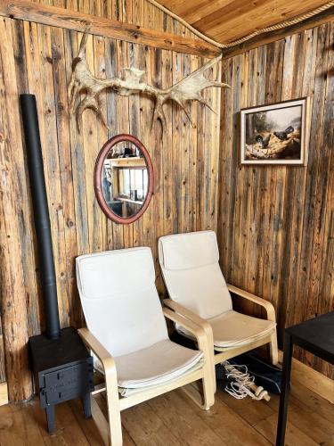 two chairs in a room with a wood wall at Haven Islands Treehouse on a private island in Torrflonäs
