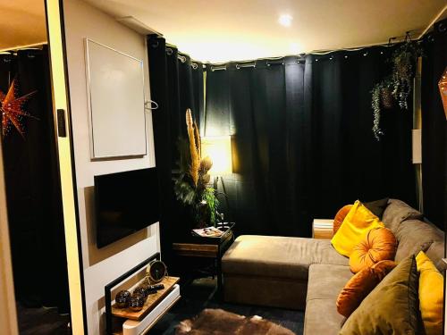 a living room with a couch and a black curtain at CAPFUN luxe chalet Onthaasten op de Veluwe za tm za in Doornspijk