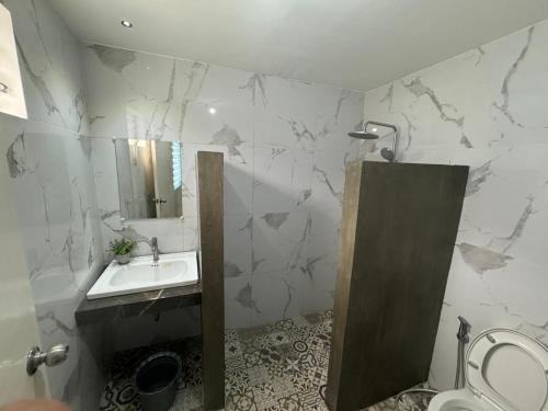 a bathroom with a sink and a toilet and a mirror at GreenEscape Beach Resort in Puerto Galera