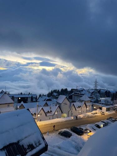 a snow covered city with houses and cars parked at Pogled Apartman Kopaonik in Kopaonik