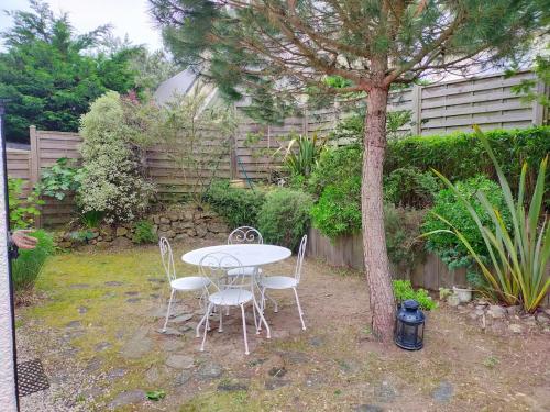 une table, des chaises et un arbre dans la cour dans l'établissement Maison des dunes - Proche mer, à Barneville-Carteret