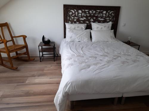 une chambre avec un lit blanc avec une tête de lit en bois dans l'établissement maison entiére, à La Celle-sous-Gouzon