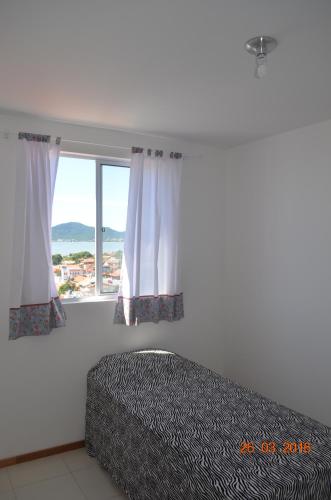 a bedroom with a bed and a large window at Residencial Lunata in Penha