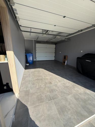 an empty garage with a garage door and a tiled floor at L ecrin de Rosheim, villa d exception, piscine in Rosheim