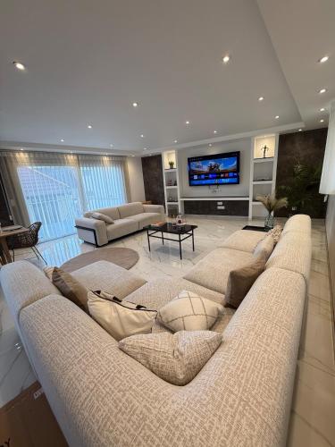 a large living room with a large couch and a television at L ecrin de Rosheim, villa d exception, piscine in Rosheim
