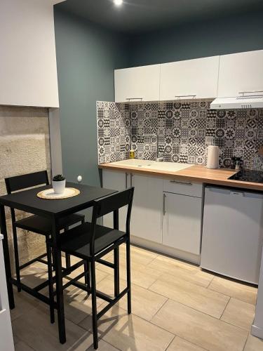 une cuisine avec une table noire et des chaises dans l'établissement Appartement, à Périgueux