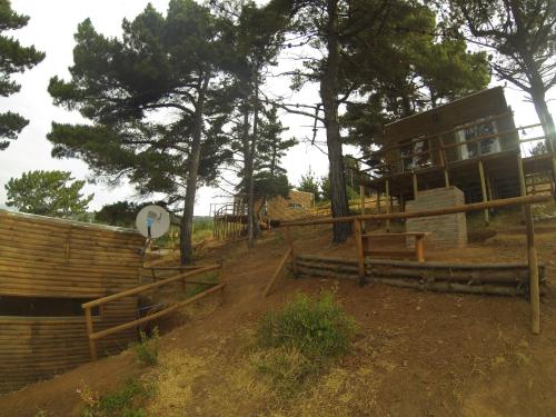 a building with a fence and a sign and trees at Cabañas & SPA Carilafquen in Laguna Verde
