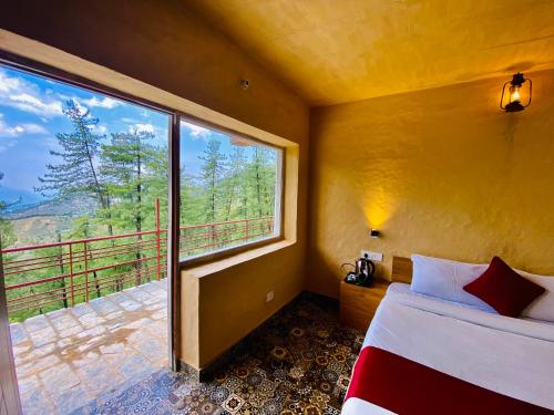 a bedroom with a bed and a large window at Staycation Premium Mud House with Balcony Mashobra - A Nature Retreat in Shimla