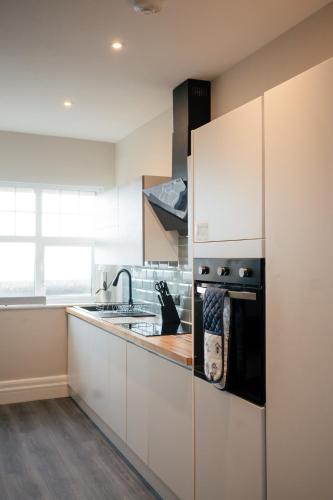 a kitchen with white cabinets and a stove top oven at Stunning 2 Bedroom Sea View Apartment With Parking in Rhos-on-Sea