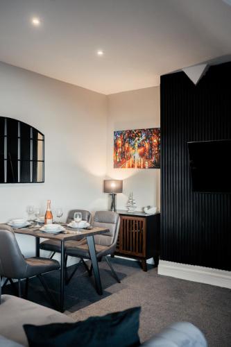 a living room with a table and chairs and a painting at Stunning 2 Bedroom Sea View Apartment With Parking in Rhos-on-Sea