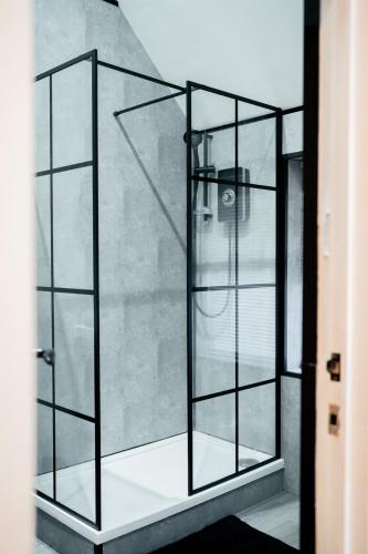 a shower with glass doors in a room at Stunning 2 Bedroom Sea View Apartment With Parking in Rhos-on-Sea