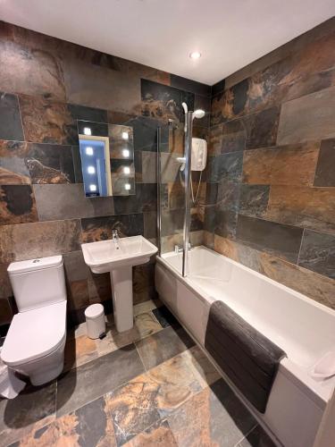 a bathroom with a toilet and a sink and a tub at Ambleside 3 Bedroom Apartment in Ambleside