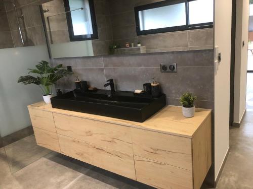 La salle de bains est pourvue d'un lavabo noir sur un comptoir en bois. dans l'établissement Villa garrigue, à Nîmes