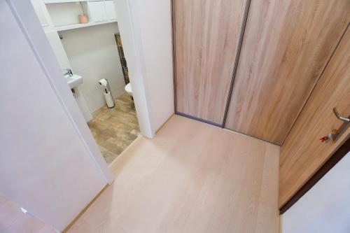 a bathroom with a wooden door and a toilet at Apartmán ARTE Spišská Nová Ves in Spišská Nová Ves