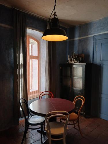 a dining room with a table and chairs and a lamp at apartmán Port Arthur in Manětín