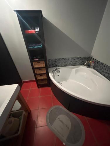 La salle de bains est pourvue d'une baignoire et d'un sol rouge. dans l'établissement Maison de vacances 15 mn de la mer avec piscine hors sol, à Languidic