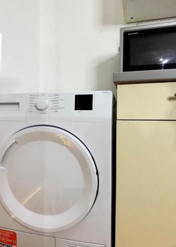 a white washing machine sitting next to a microwave at 1 private room & a toilet in 2bed apartment in Manchester