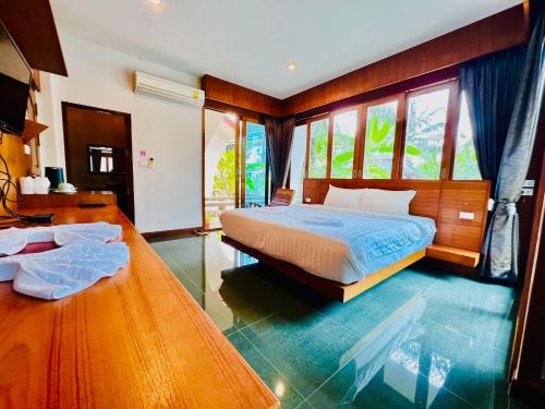 a bedroom with a bed and a table and windows at บ้านสวนวารินทร์ in Ban Na Nian