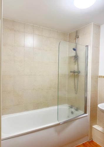 a bath tub with a glass shower in a bathroom at 1 private room & a toilet in 2bed apartment in Manchester