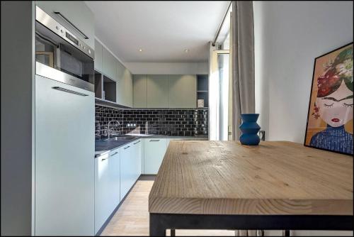 une cuisine avec des armoires blanches et une table en bois dans l'établissement Suite ana, à Nice