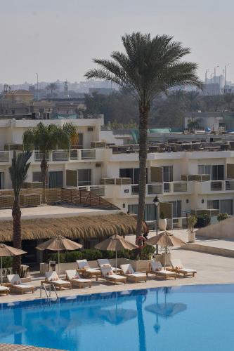 a hotel with a pool with chairs and umbrellas at Pyramids Park Resort Cairo in Cairo
