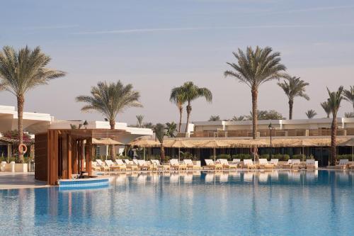 a resort with a large swimming pool with chairs and palm trees at Pyramids Park Resort Cairo in Cairo