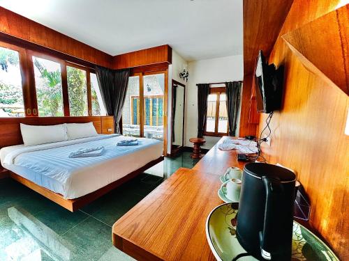 a bedroom with a bed and a desk with a television at บ้านสวนวารินทร์ in Ban Na Nian