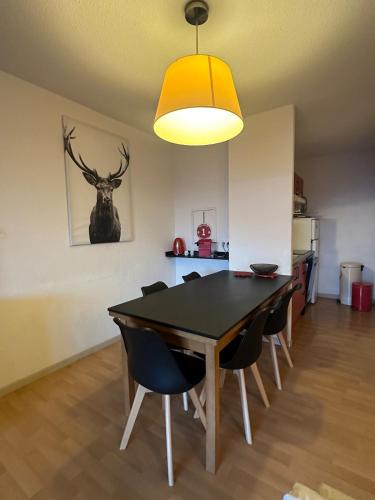 une salle à manger avec une table et des chaises noires dans l'établissement Font -Romeu grand T4 en résidence vue magnifique, à Font-Romeu-Odeillo-Via
