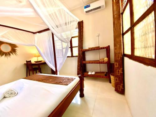 a bedroom with a canopy bed and a window at Samsara Beach House in Kiganga
