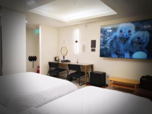 a bedroom with a bed and a desk with a monitor on the wall at Bluebird Hotel in Incheon