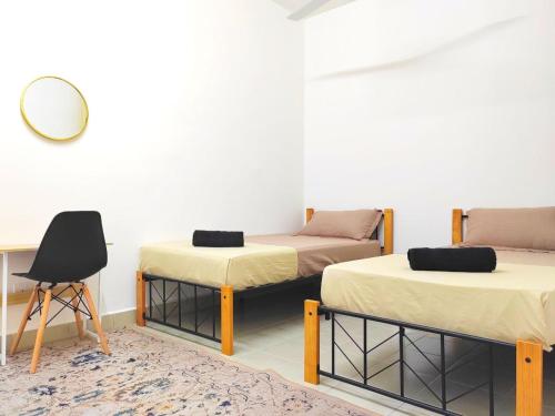two beds in a room with a mirror and a chair at GRANDE MAISON 3 NEAR AFAMOSA WaterPark in Kampong Pulau Sebang