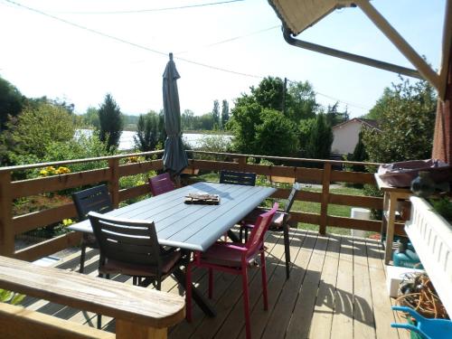a table and chairs on a deck with an umbrella at Maison patio et piscine in Feillens