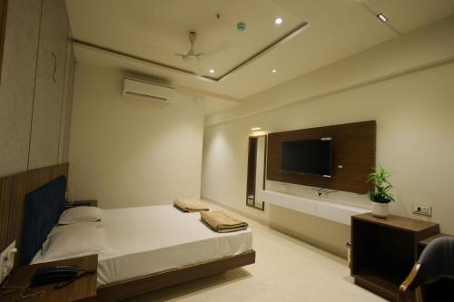 a bedroom with a bed and a flat screen tv at Hotel Shubhkarta in Akola
