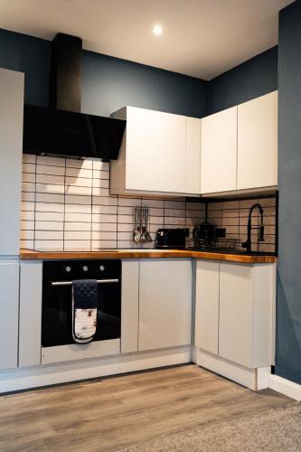 a kitchen with white cabinets and a stove top oven at Stunning 2 Bedroom Beach Apartment With Garden in Rhos-on-Sea
