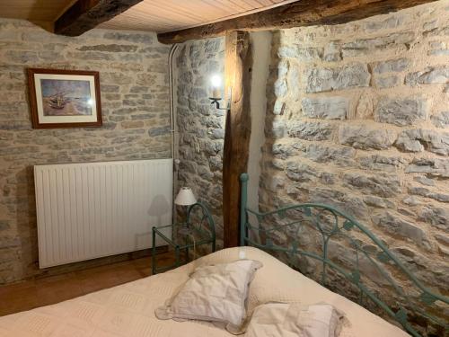 une chambre avec un lit et un mur en pierre dans l'établissement Mas d'Ambayrac chambres d'hôte Le bolet, à Promilhanes
